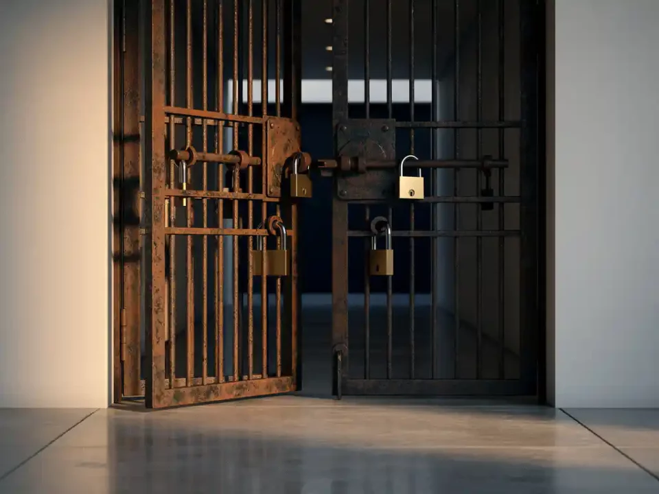 Heavy iron gate with rust patina showing three lock positions in a modern corridor with warm amber lighting and polished concrete floors.
